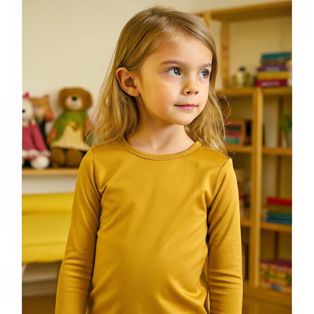 A child wearing a yellow long-sleeve top and matching pants from a bamboo pajama set.
